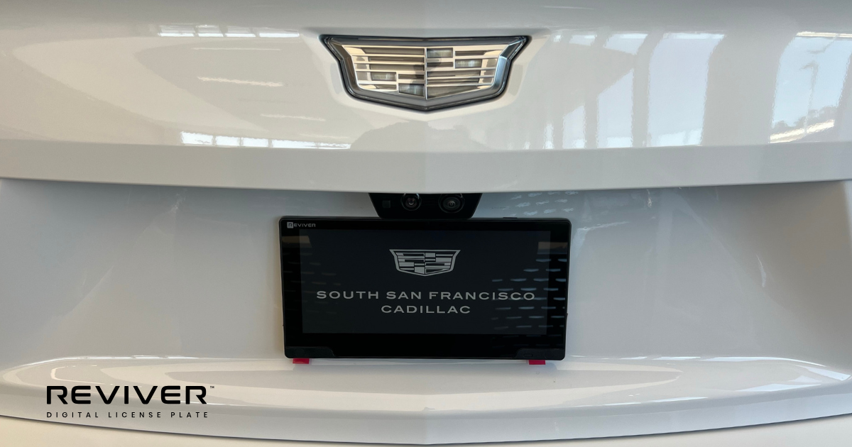 Image of a white Cadillac with a digital license plate.